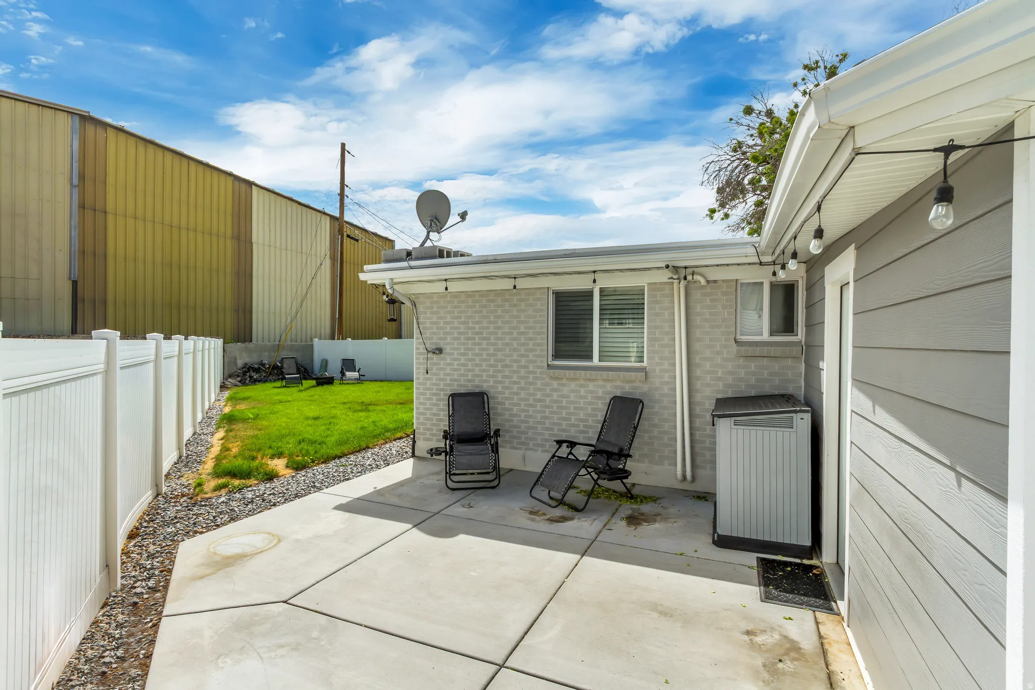 Outdoor patio with concrete surfacing, white vinyl fencing, and a manicured lawn area
