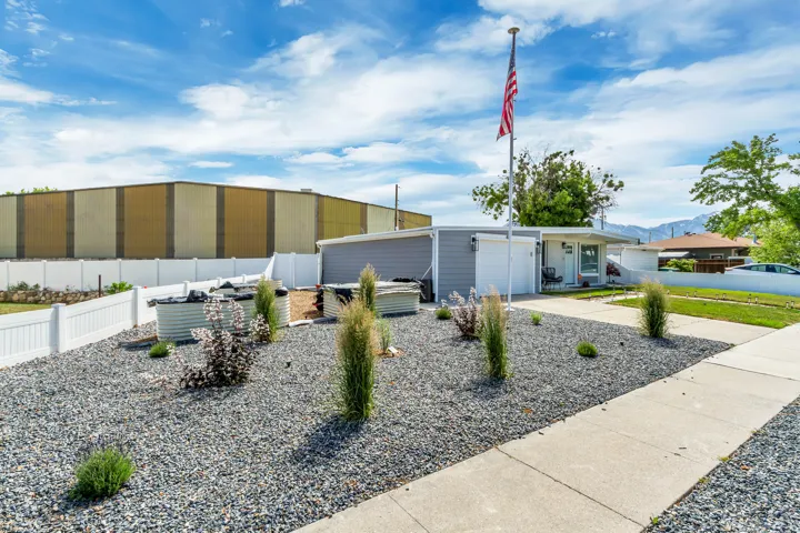 Landscaped front yard with gravel, a concrete walkway, and a white picket fence