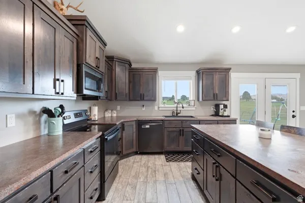 Galley kitchen with dark wood-finish cabinetry, built-in stainless steel appliances, a center island with countertop seating, recessed lighting, and wood-finish flooring