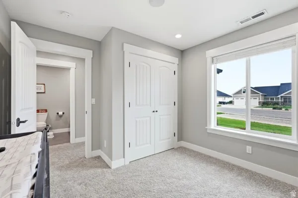 Recessed lighting, light gray wall color, white trim throughout, carpeted flooring, and a double-door closet