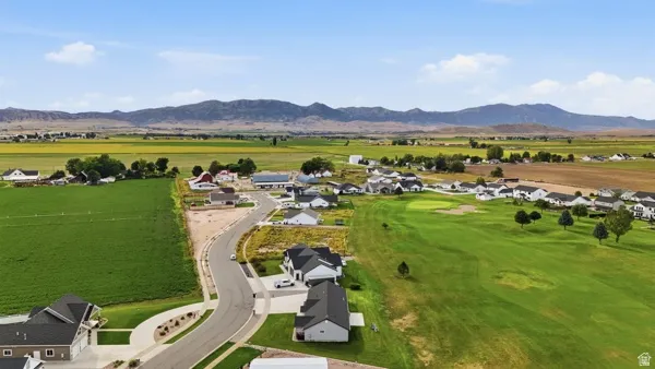 Expansive community featuring golf course access, surrounding agricultural fields, and distant mountain scenery
