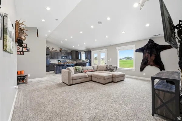 Spacious open-concept living area with vaulted ceilings, recessed lighting, and light-toned carpeting