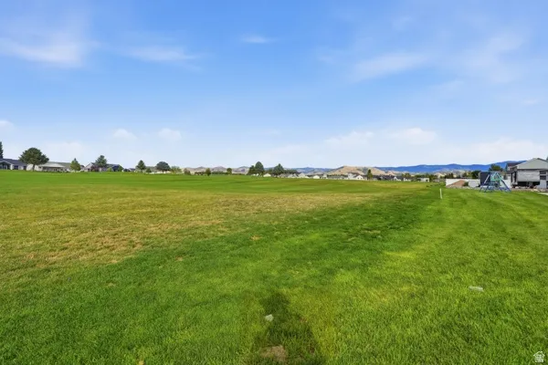 Expansive green space featuring a distant residential backdrop and distant mountain scenery