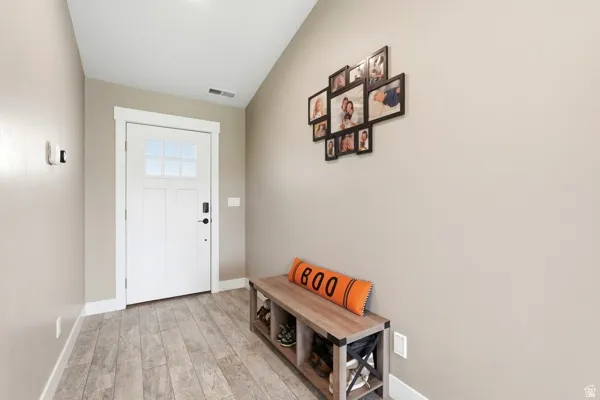 Entryway with a white paneled door featuring multiple lites, complemented by wood-finish flooring, and light neutral wall paint