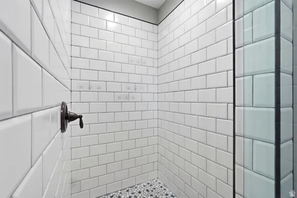 Shower enclosure featuring white subway tile walls, a mosaic tile floor, an oil-rubbed bronze fixture, and a glass panel