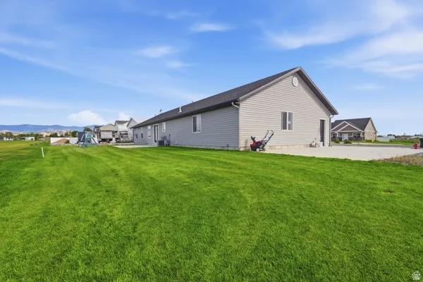 Expansive green lawn with a gravel driveway and a light-colored siding exterior