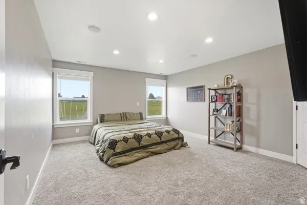 Plush carpet flooring, recessed lighting, dual windows with white trim, and light gray wall paint