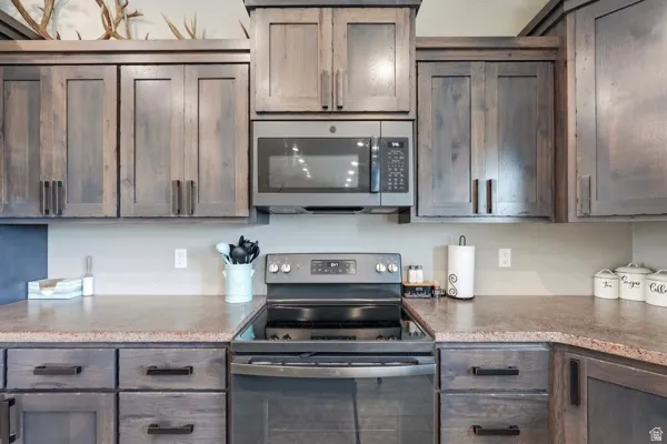 Kitchen featuring wood-finish cabinetry, stainless steel microwave, and range