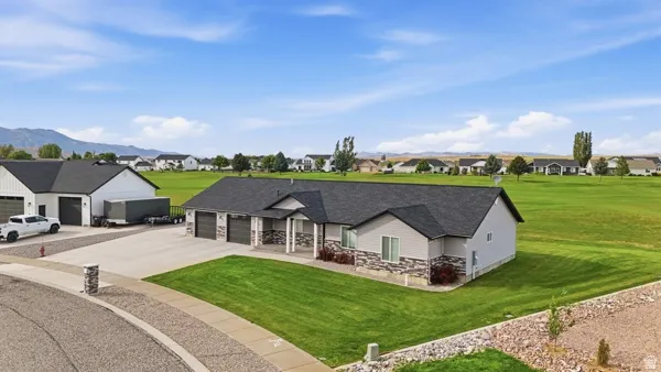 Ranch-style residence featuring a prominent stone facade, three-car garage, and an expansive manicured lawn