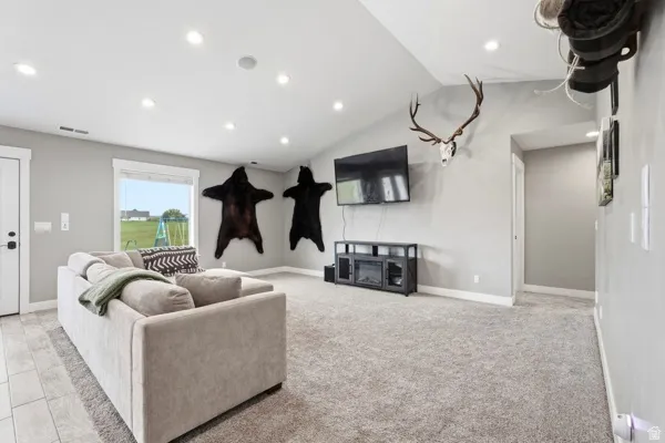 Spacious room with light gray walls, recessed lighting, a vaulted ceiling, and a large window