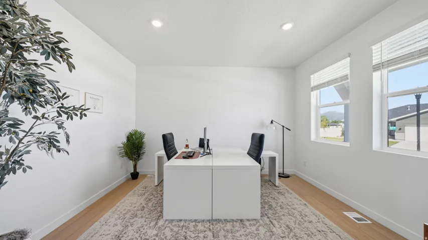 Recessed lighting, wood-finish flooring, and white walls create a bright interior