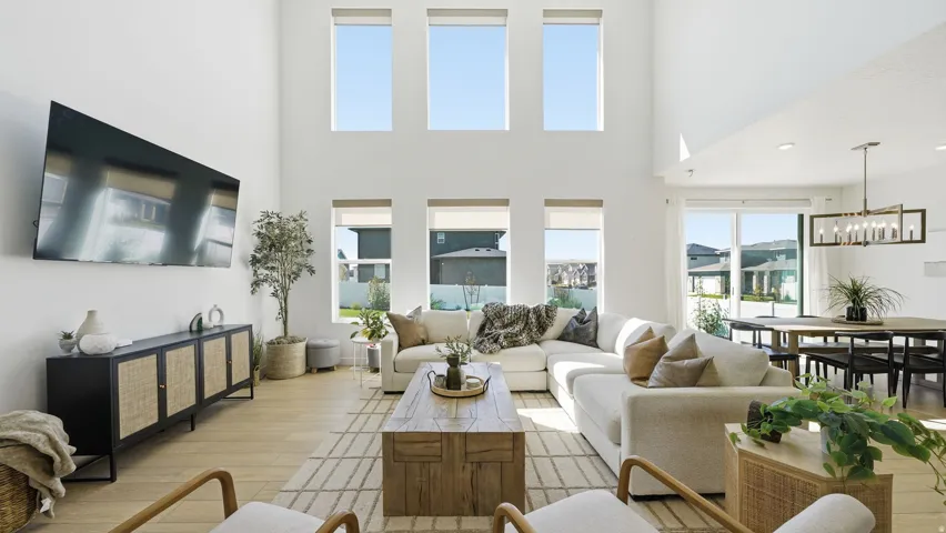 Vaulted ceilings with abundant natural light, light wood-finish flooring, and a modern chandelier