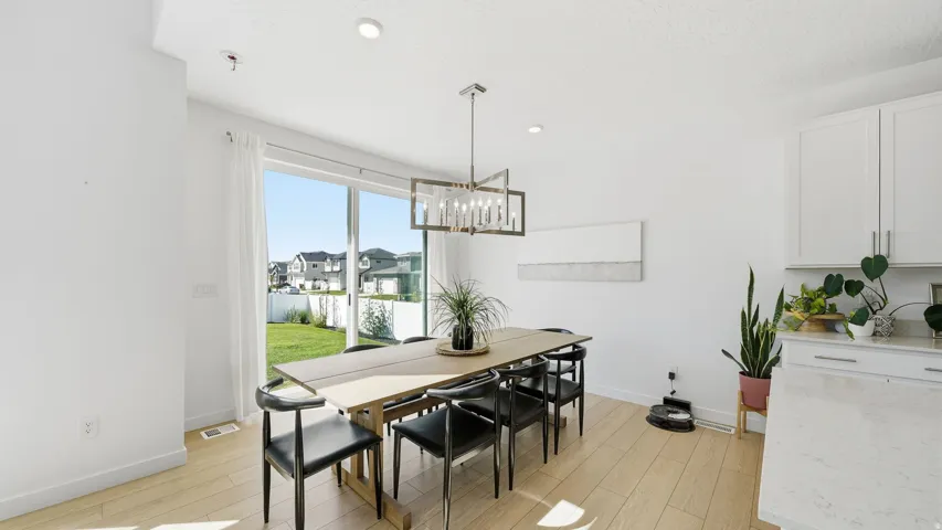 Sliding glass door, wood-finish flooring, recessed lighting, modern chandelier, and light-colored cabinetry