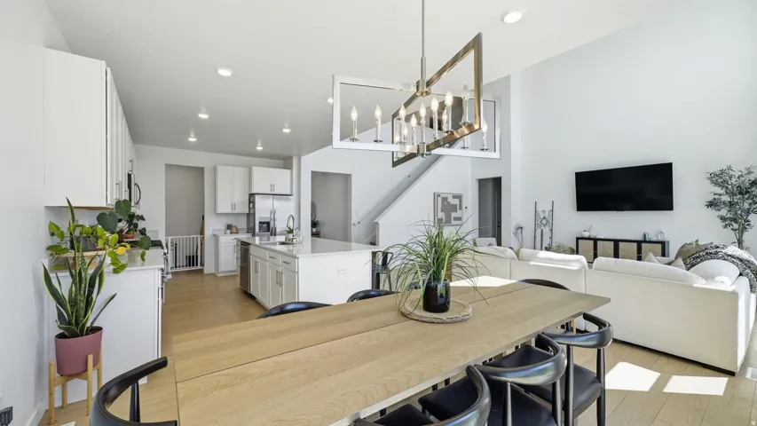 Vaulted ceilings with a statement chandelier, white cabinetry, a kitchen island with seating, recessed lighting, and light wood-finish flooring
