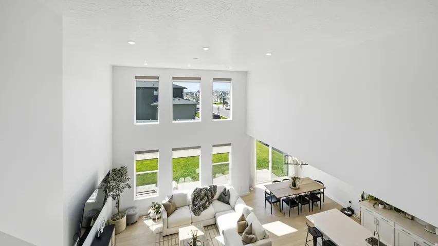 Two-story living area with multiple windows, recessed lighting, wood-finish flooring, and a white kitchen island