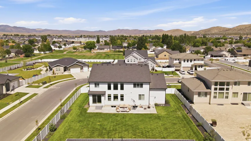 Expansive green lawn, white fencing, and a concrete patio with steps