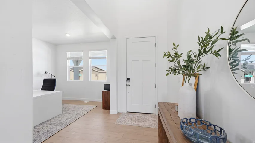 Entryway with light wood-finish flooring, white paneled door, and recessed lighting