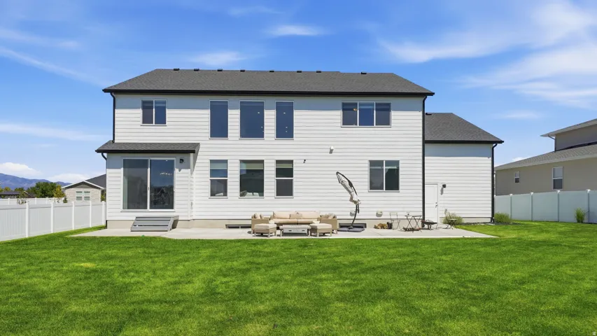Expansive rear exterior with white siding and a dark shingle roof
