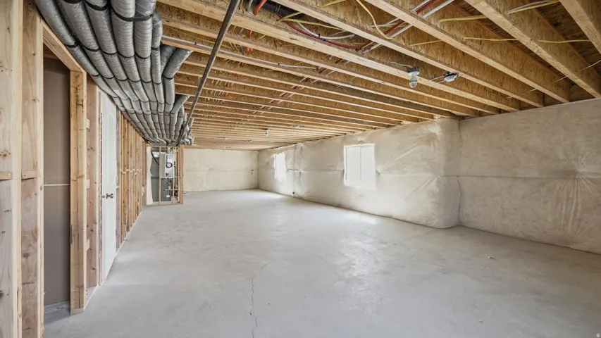 Unfinished basement with exposed wood framing, concrete flooring, and insulated foundation walls