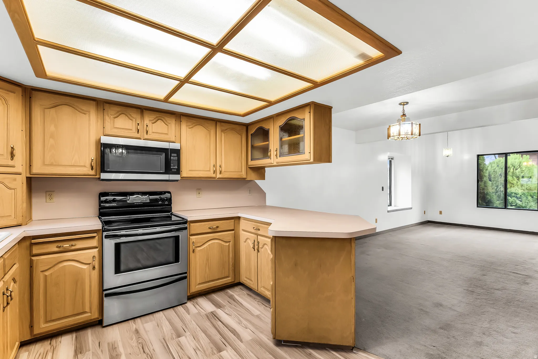 Kitchen featuring wood-finish cabinetry, stainless steel microwave, and range