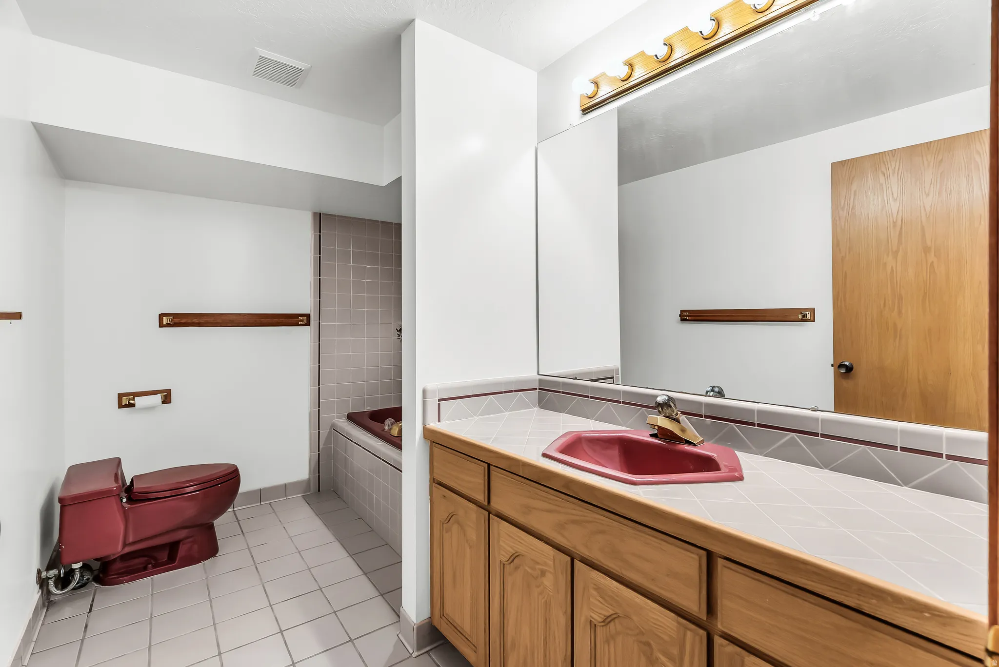 Integrated vanity with wood-finish cabinetry, a drop-in sink, and a large wall-mounted mirror