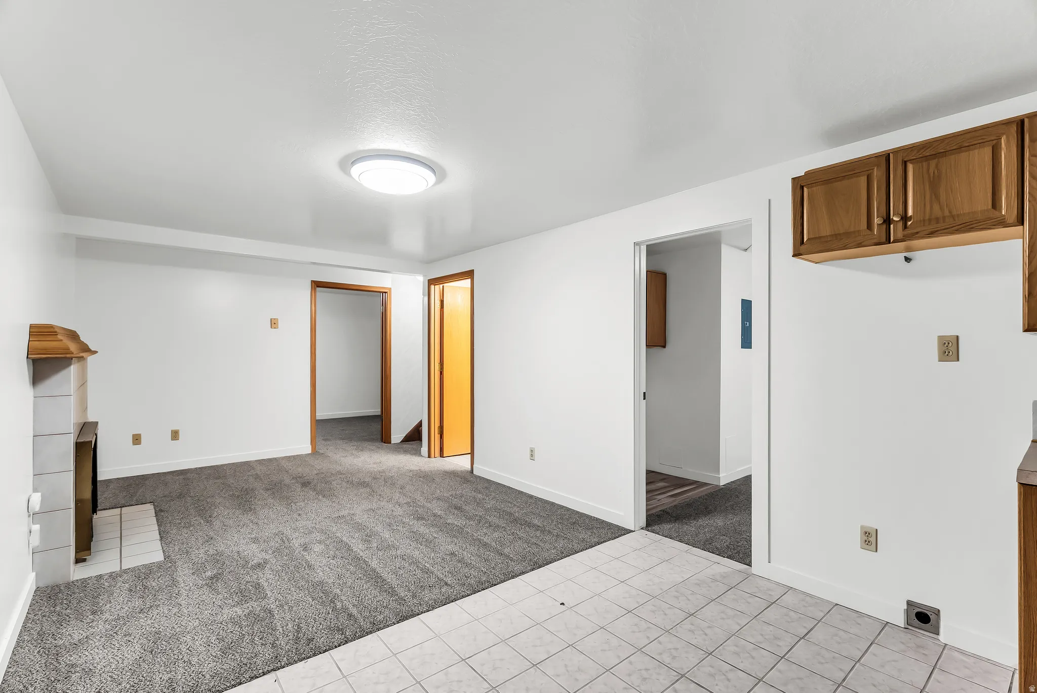 White painted walls with wood-finish trim, gray carpeting, and a tiled fireplace surround