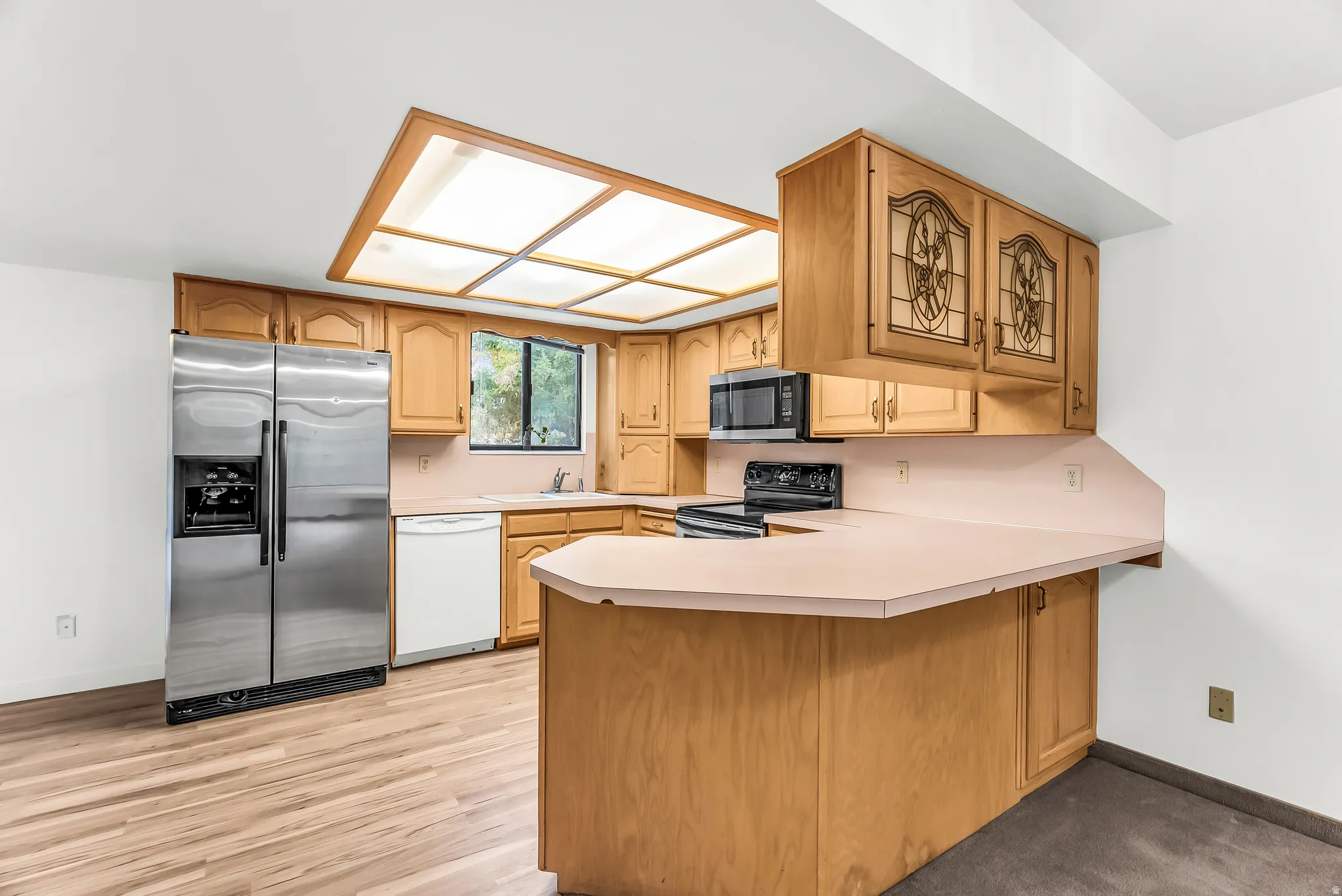 Kitchen featuring wood-finish flooring, recessed ceiling lighting, light-toned cabinetry, and stainless steel appliances