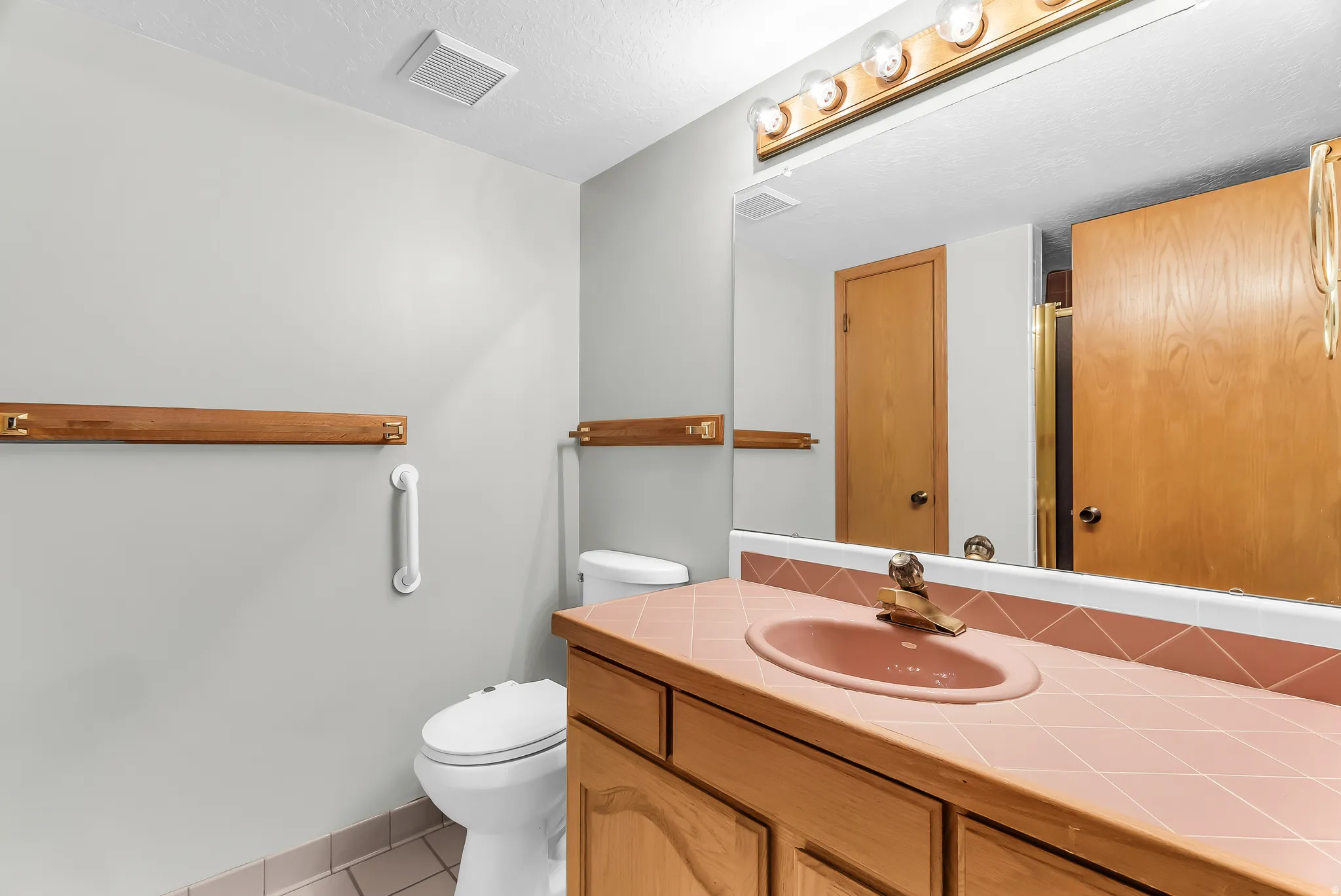 Extended vanity with integrated sink, full-width wall mirror, and overhead strip lighting