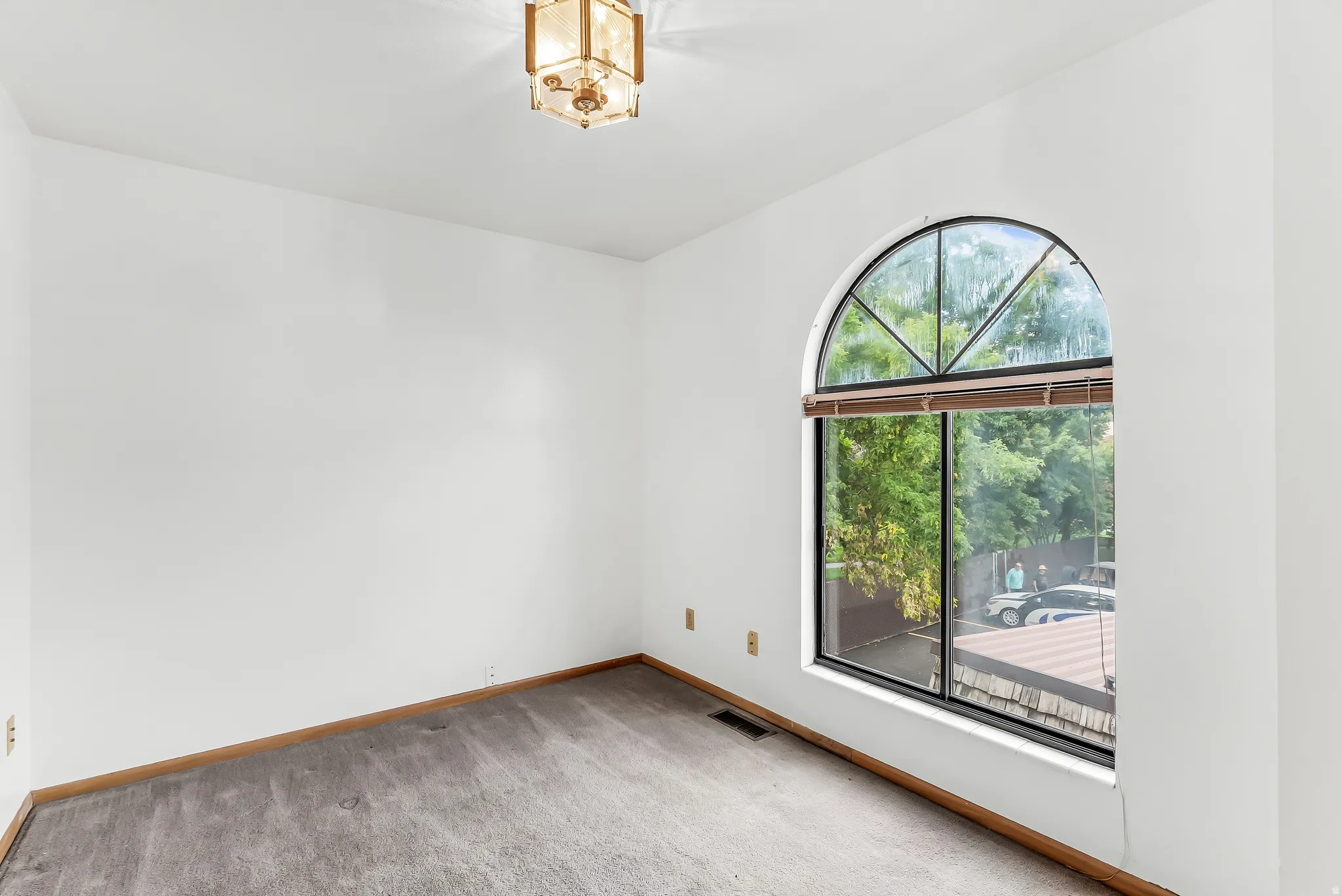 Arched window with wood blinds and a geometric light fixture