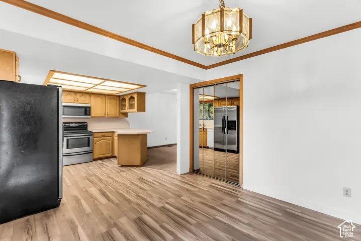 Wood-finish flooring, overhead lighting fixture, wood trim, kitchen cabinetry, and mirrored closet doors