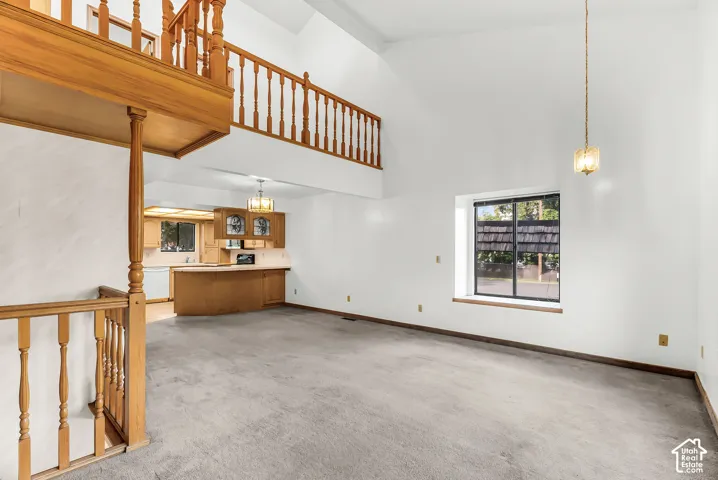 Vaulted ceilings, open loft, wood-finish railing, kitchen with wood cabinetry, and a large window