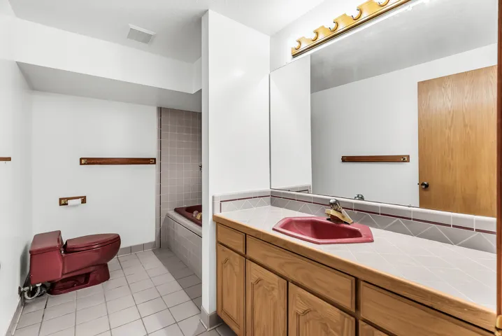 Integrated vanity with wood-finish cabinetry, a drop-in sink, and a large wall-mounted mirror