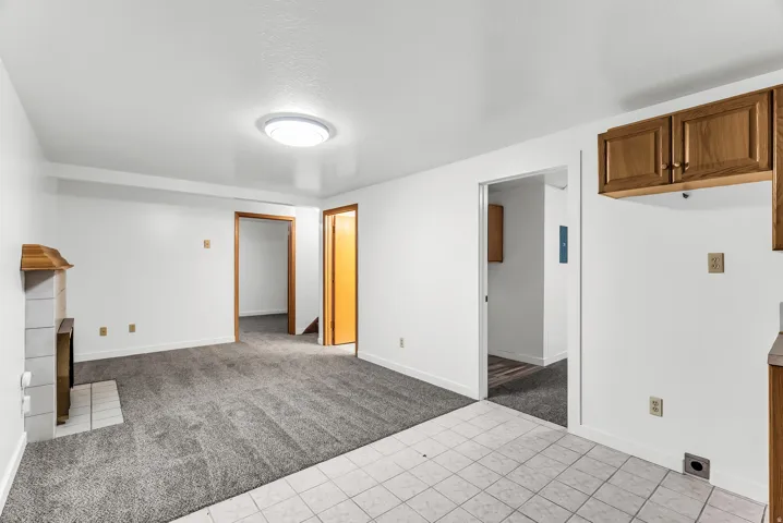 White painted walls with wood-finish trim, gray carpeting, and a tiled fireplace surround