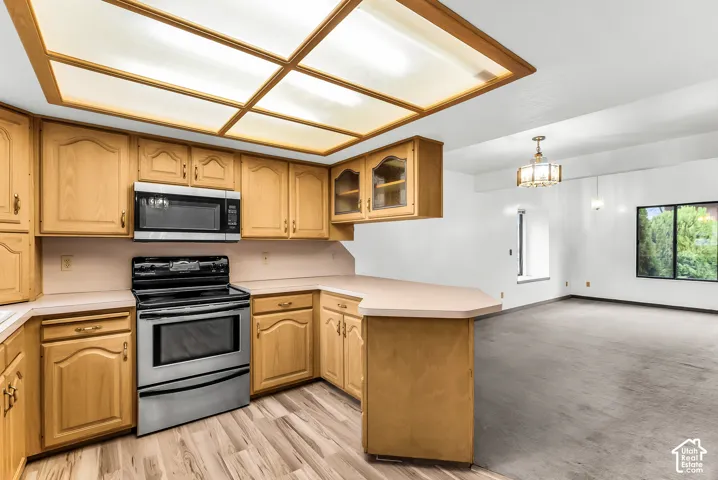 Kitchen featuring wood-finish cabinetry, stainless steel microwave, and range