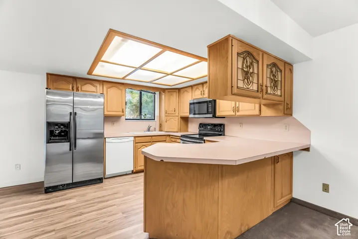 Kitchen featuring wood-finish flooring, recessed ceiling lighting, light-toned cabinetry, and stainless steel appliances