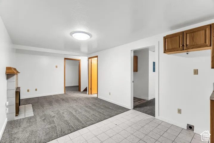 White painted walls with wood-finish trim, gray carpeting, and a tiled fireplace surround