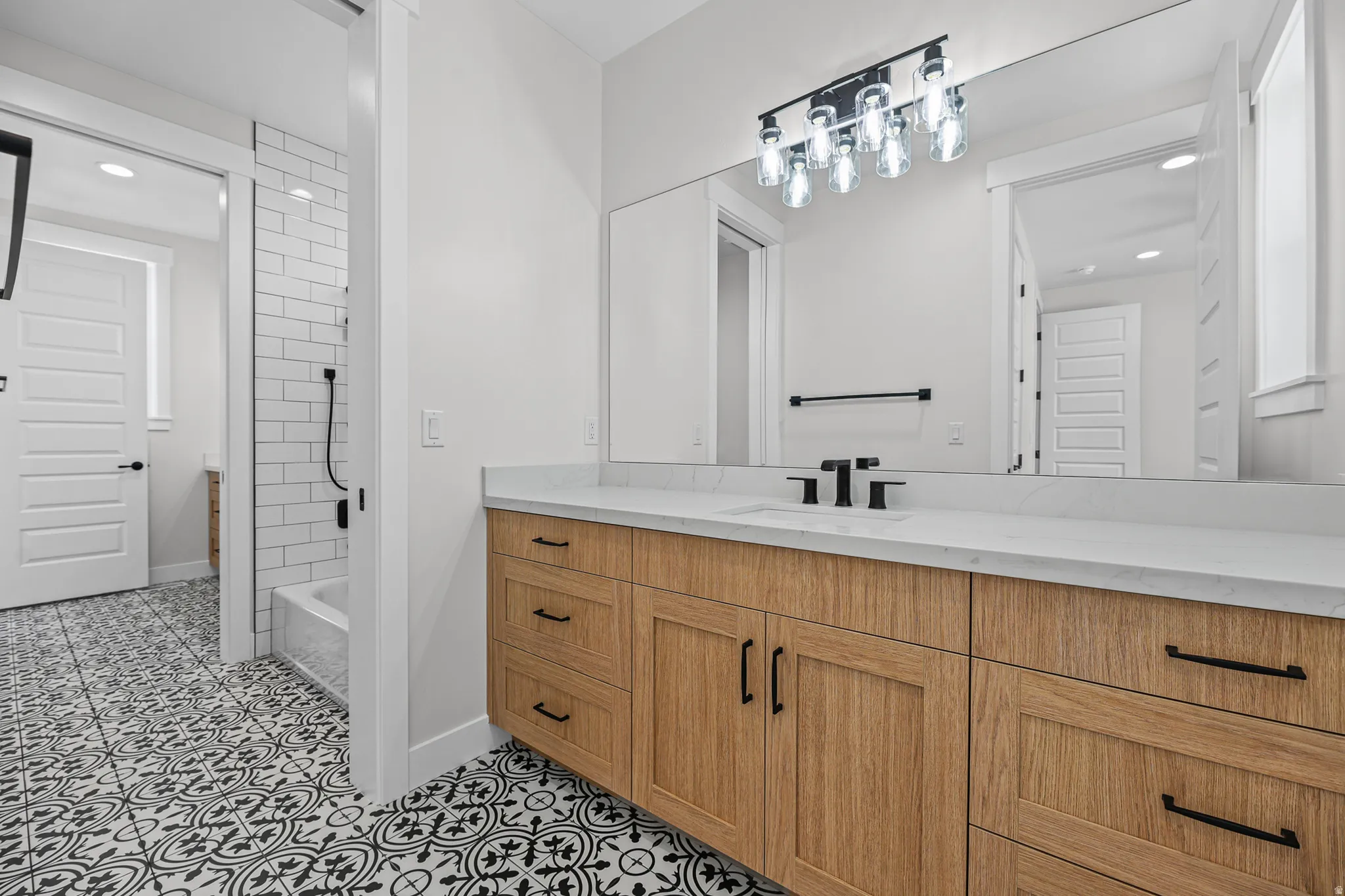Wood-finish vanity with black hardware, white countertop, and integrated sink