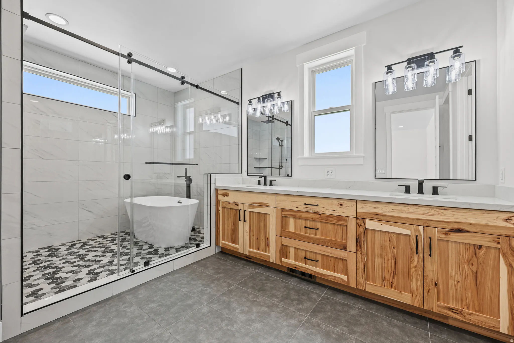 Glass-enclosed shower with a freestanding soaking tub, dual vanity with wood-finish cabinetry, and stone countertops