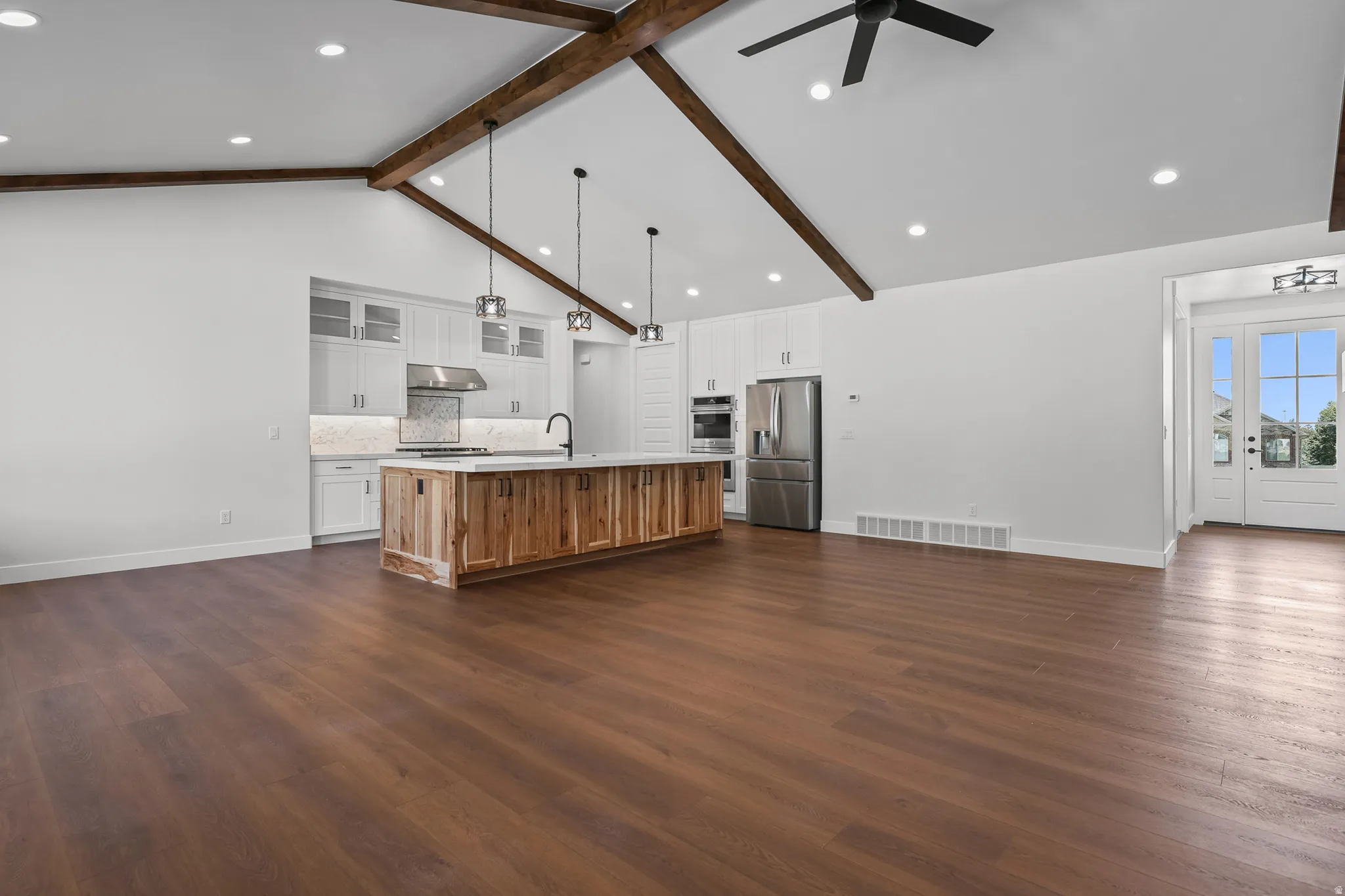 Vaulted ceiling with exposed wood beams, wood-finish flooring, recessed lighting, and a kitchen island with pendant lighting