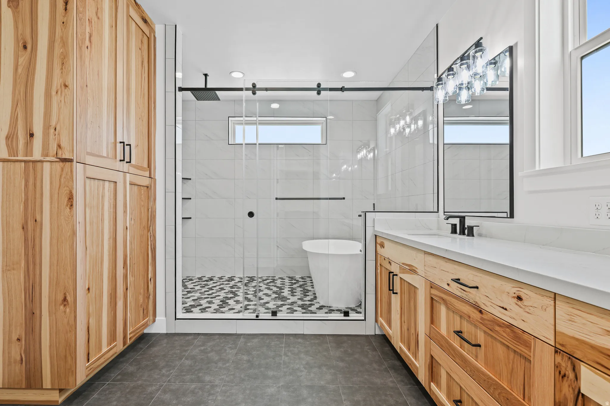 Walk-in shower with patterned tile flooring, freestanding tub, and a rain showerhead