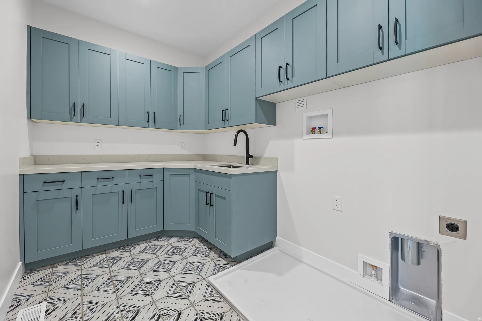 Extensive cabinetry with matte black hardware, light-toned countertops, and a built-in sink with a matte black faucet
