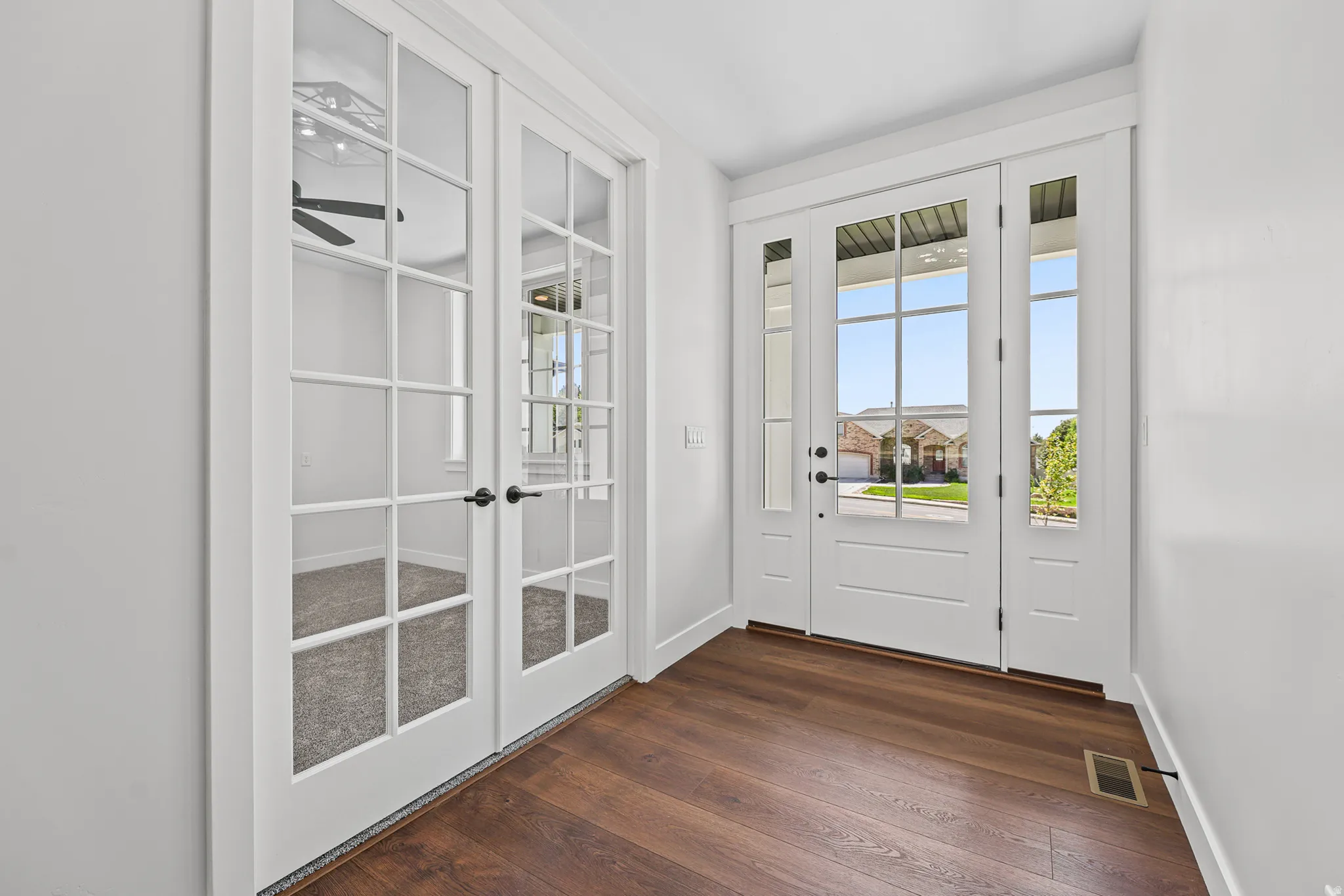 Entry featuring a white multi-pane front door, side windows, and wood-finish flooring