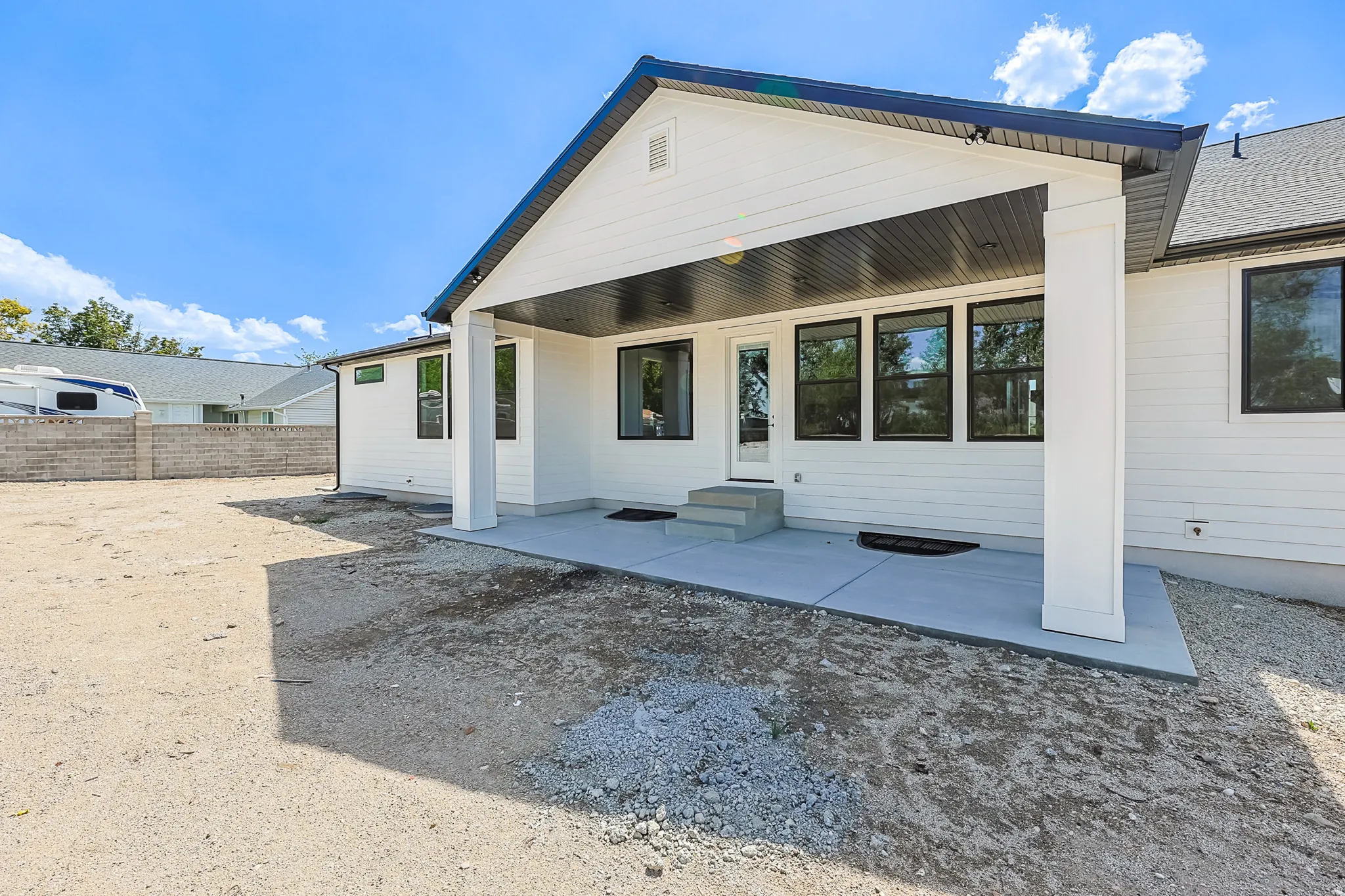 Covered concrete patio with white siding and black-trimmed windows