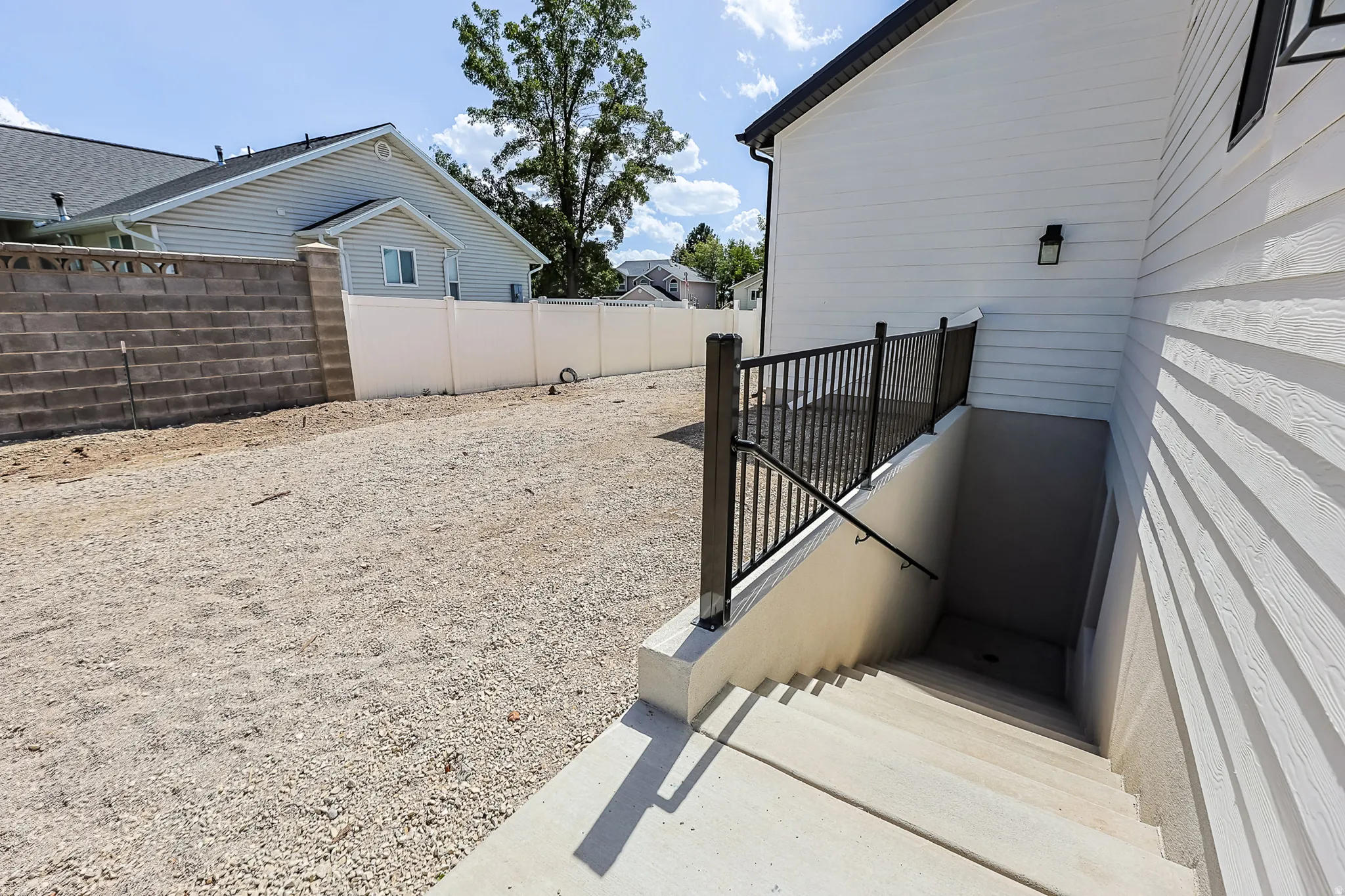 Exterior basement access with concrete steps, black metal railing, and an outdoor light fixture