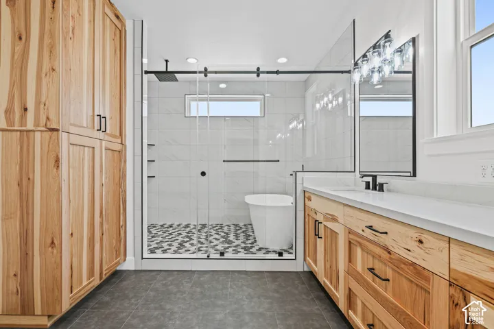 Walk-in shower with patterned tile flooring, freestanding tub, and a rain showerhead