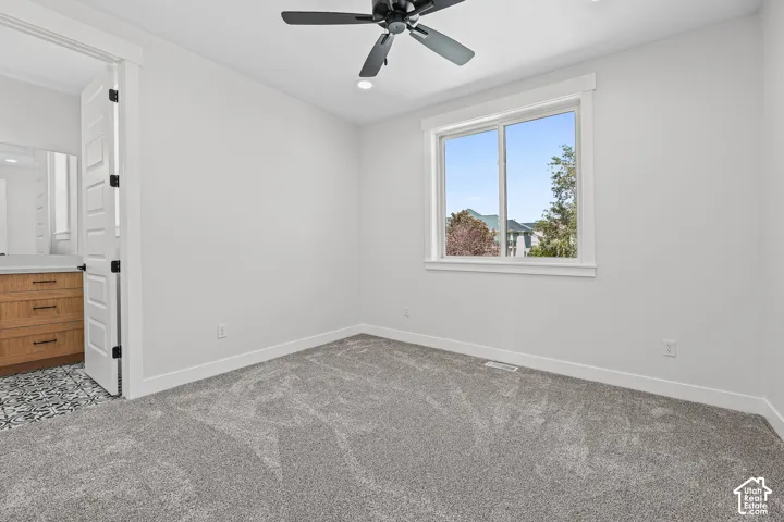 Plush gray carpeting with bright white walls, a black ceiling fan, and a large window with white trim