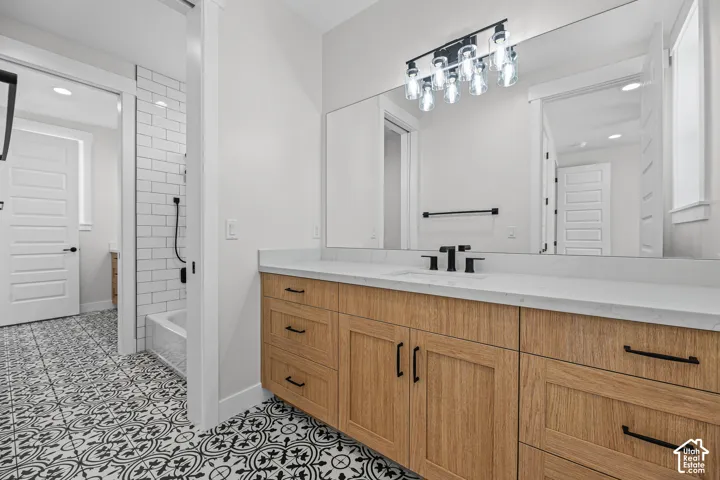 Wood-finish vanity with black hardware, white countertop, and integrated sink