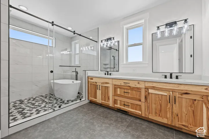 Glass-enclosed shower with a freestanding soaking tub, dual vanity with wood-finish cabinetry, and stone countertops