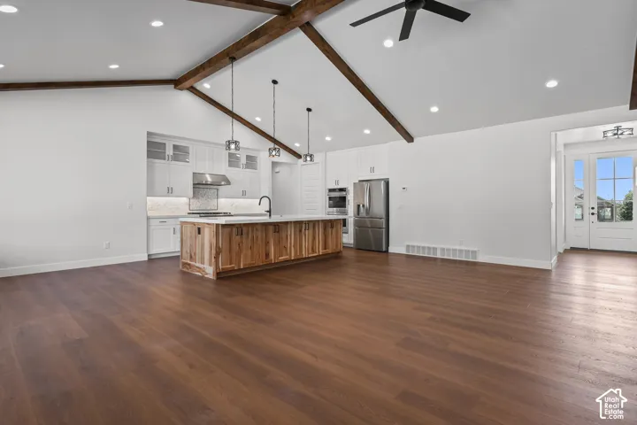 Vaulted ceiling with exposed wood beams, wood-finish flooring, recessed lighting, and a kitchen island with pendant lighting