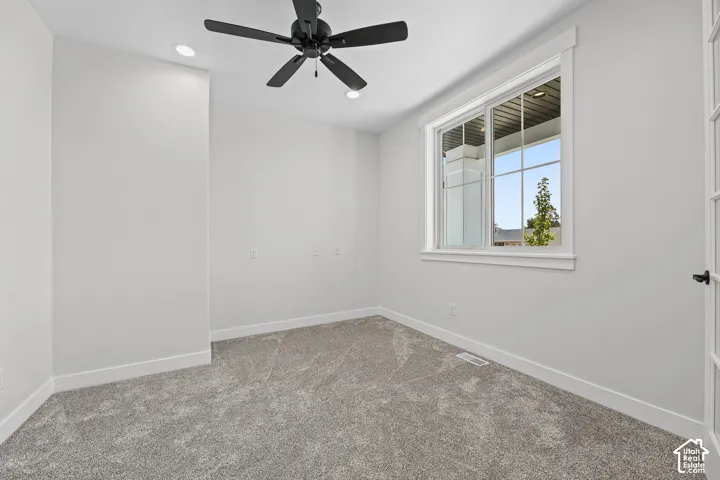 Recessed lighting, ceiling fan, grey carpeting, white trim, and a window with a multi-pane design